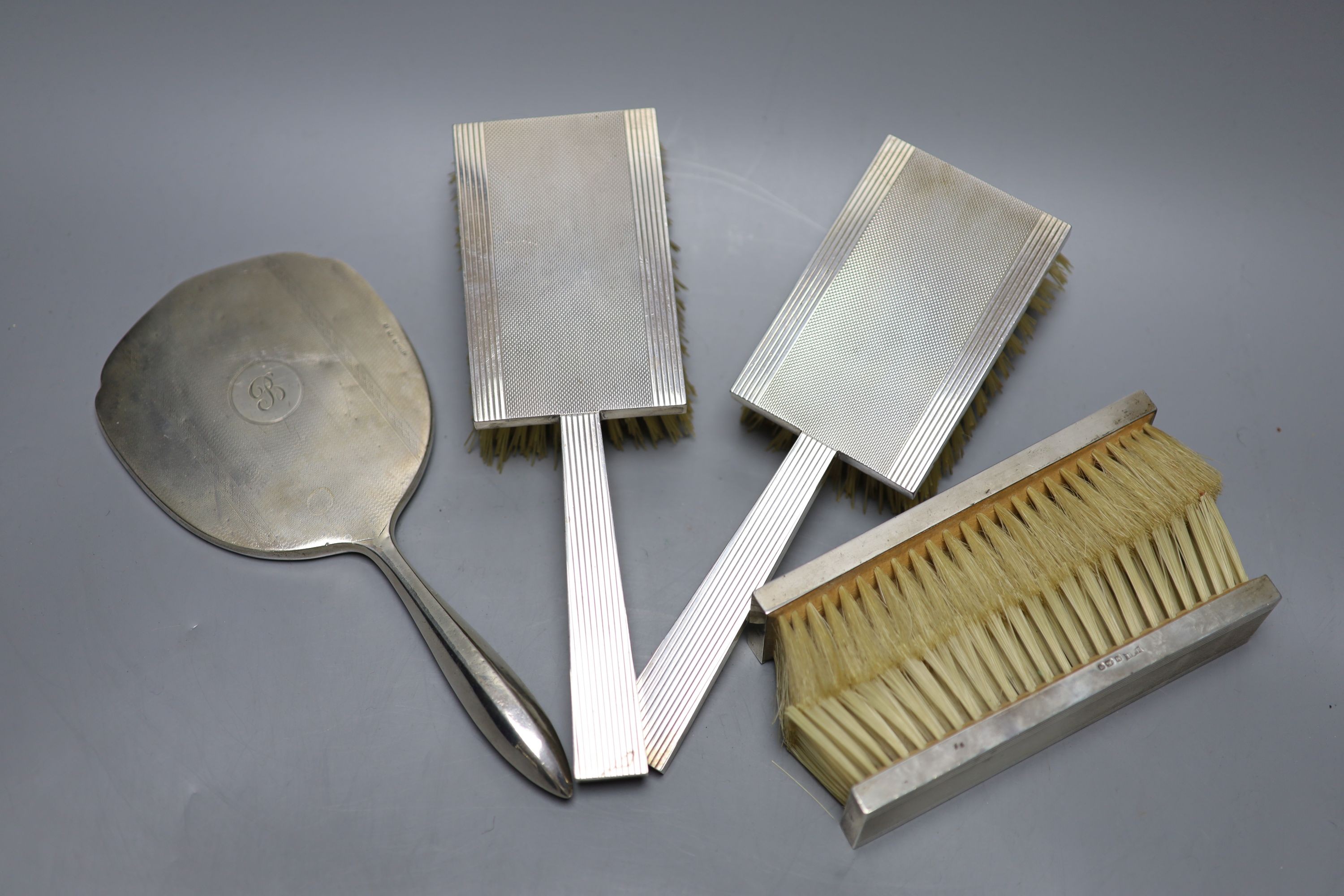 A 1930's engine turned silver backed four piece dressing table set, Birmingham, 1936 and a silver mounted hand mirror.